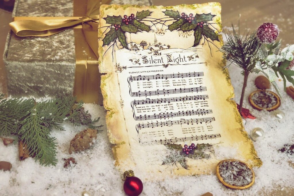 Get in the Christmas spirit with this image of decorated vintage sheet music to Silent Night sitting on a bed of frost starred with evergreens, orange slices, pinecones, and berries.